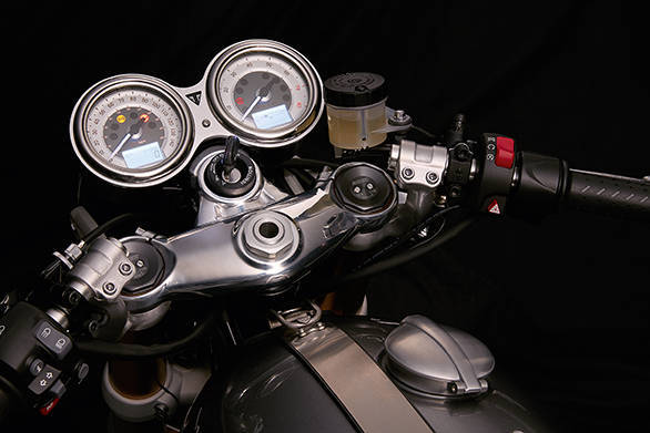 So many details to notice! The Thruxton's top yoke is polished to a mirror finish. Clip-ons mount below the top yoke. Note the aluminium faux tank retainer strap and the offset Monza-style fliptop filler cap (with a locked cap hidden inside)